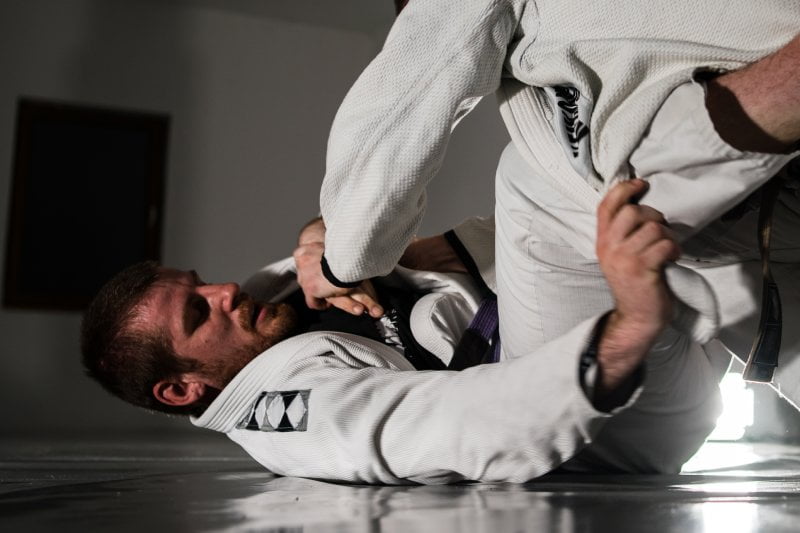 Close-up of two martial artists in gi practicing a ground control move in Judo - Judo