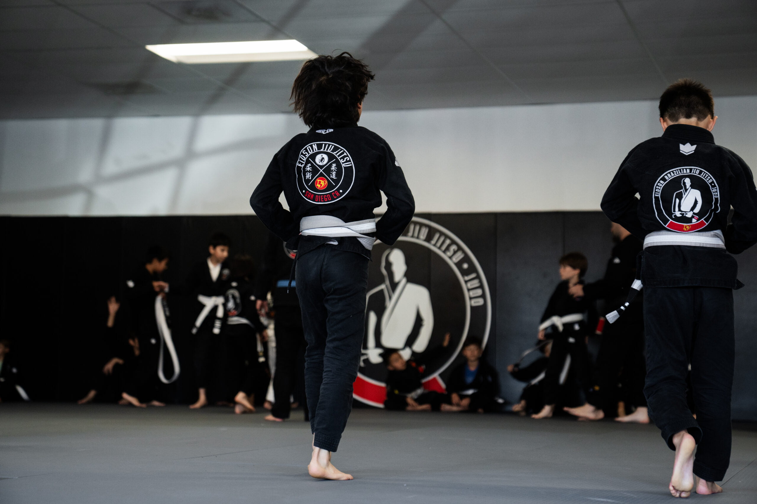 Teen students training together in martial arts teens program - Teens Program Group of teenagers in gi uniforms practicing martial arts drills on the mat during teens program - Teens Program