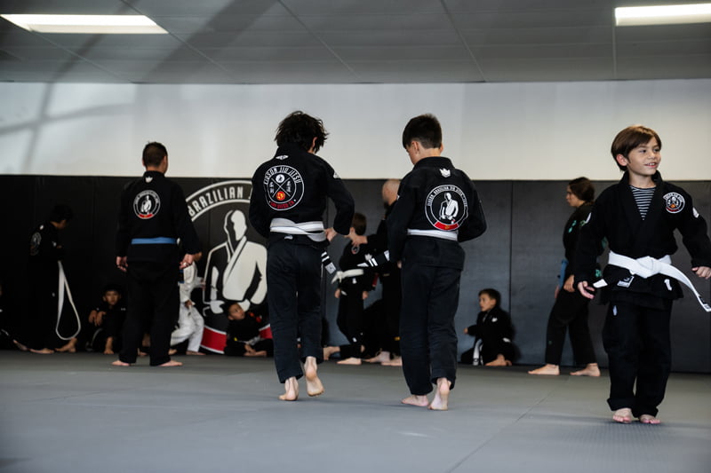 Group of kids practicing movements and drills during martial arts class in dojo setting - Martial Arts