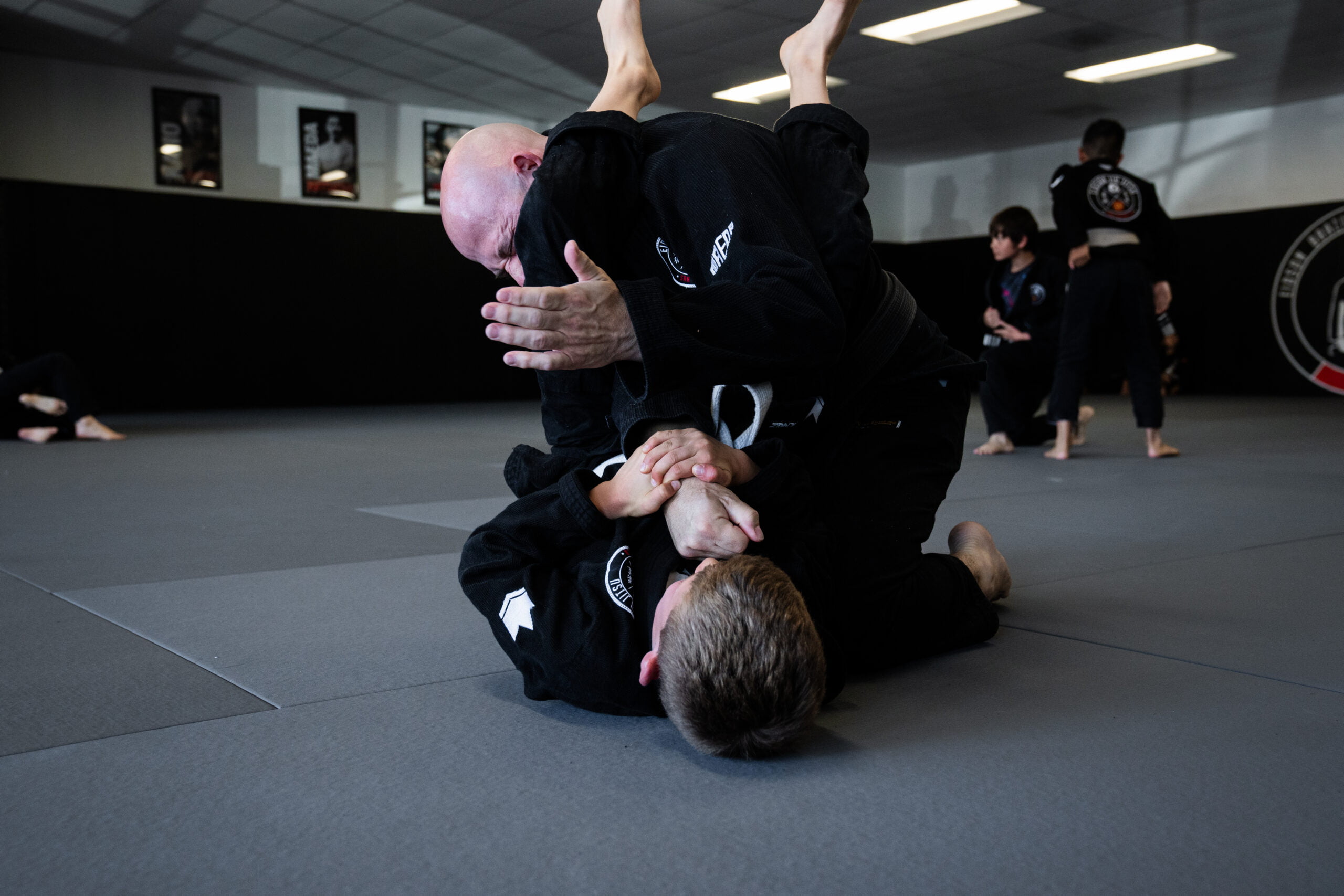 Martial arts students in gi uniforms demonstrating a grappling hold during class training session - Martial Arts
