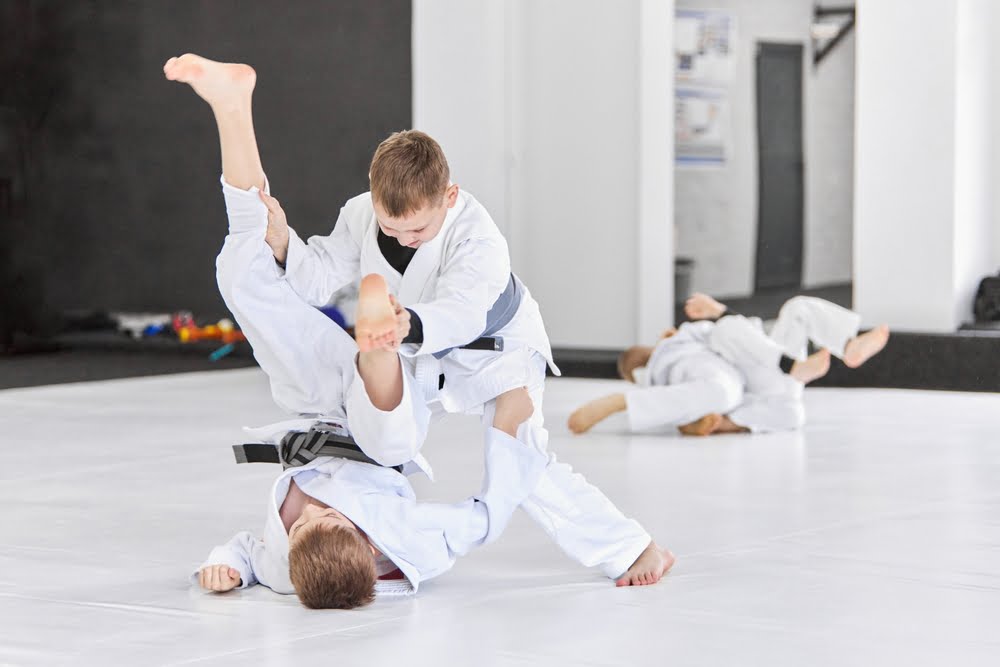Children sparring in gi uniforms on white mats during martial arts class in Poway CA - Martial Arts Poway CA