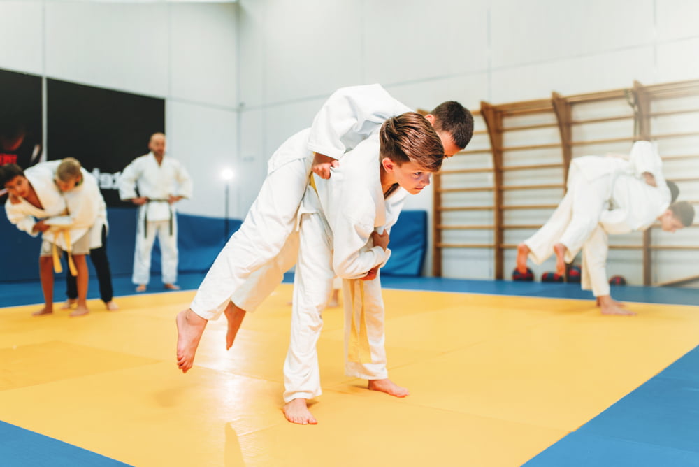 Young students in gi uniforms practicing partner throws under supervision during martial arts training in Poway CA - Martial Arts Poway CA